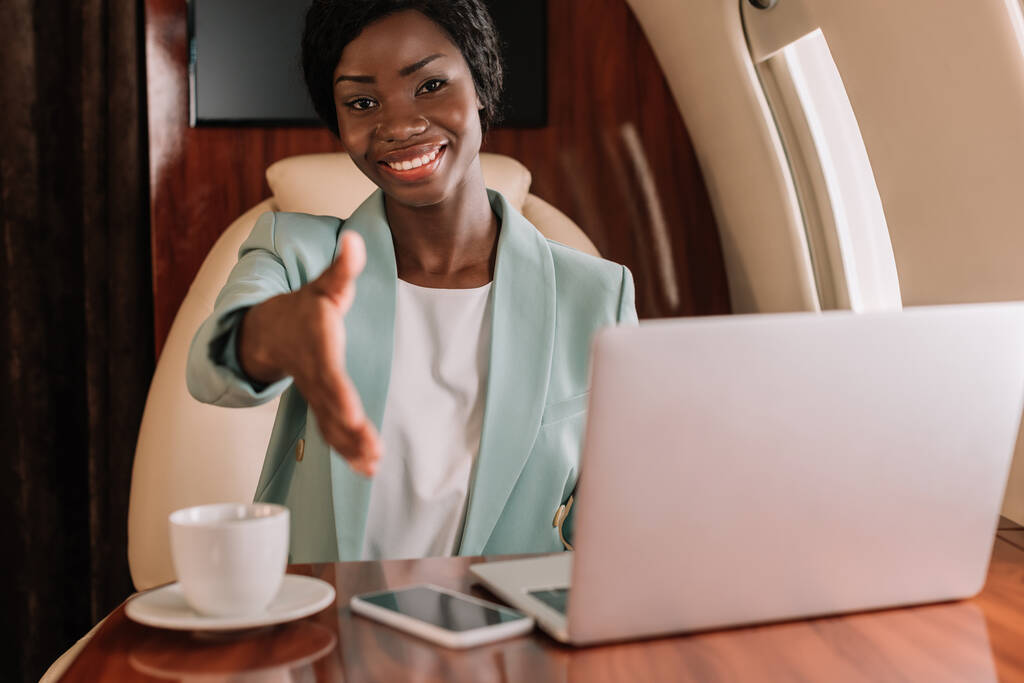 χαμογελαστή αφροαμερικανίδα επιχειρηματίας δείχνει χαιρετισμό χειρονομία με απλωμένο χέρι  - Φωτογραφία, εικόνα