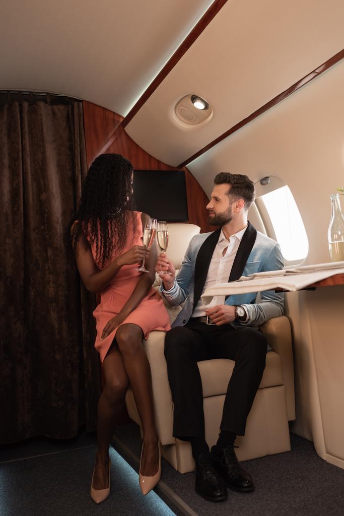 élégant couple interracial cliquetis verres de champagne tout en voyageant en jet privé
 - Photo, image