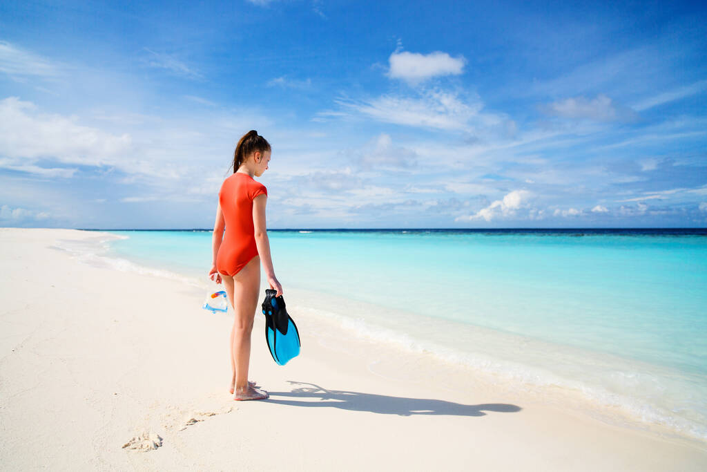Vista trasera de la adolescente con equipo de snorkel en la playa durante las vacaciones de verano
 - Foto, Imagen
