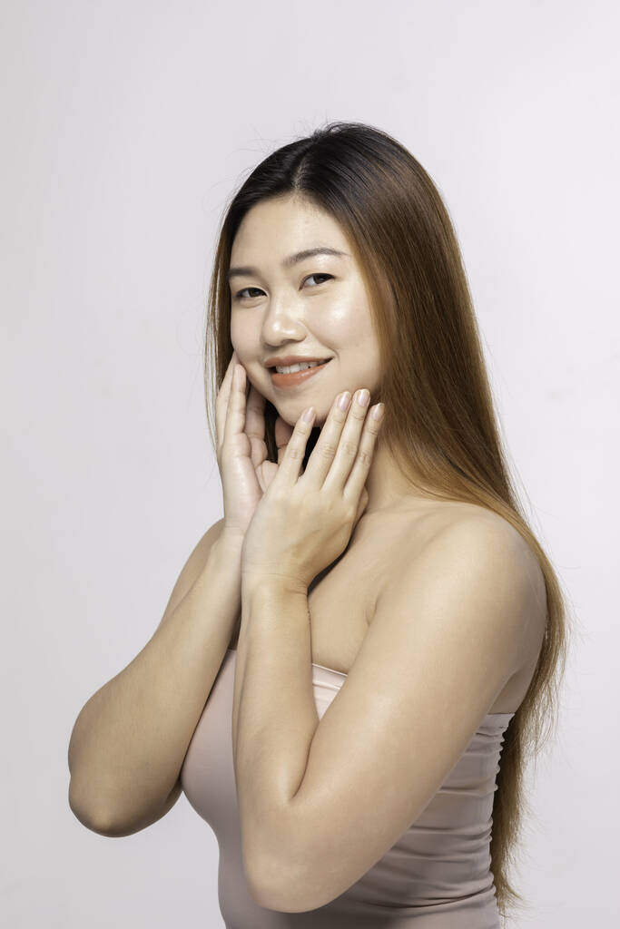 Hermosa atractiva encantadora joven asiática sonrisa con dientes blancos y tocar la mejilla suave sentirse tan feliz y alegre con la piel sana, aislado sobre fondo blanco, concepto de belleza cosmetología
 - Foto, Imagen