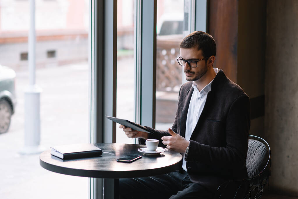 Egy férfi ül egy kávézóban táblagéppel. Alkalmi ember használata tabletta Számítógép ül Cafe Surfing Internet - Fotó, kép
