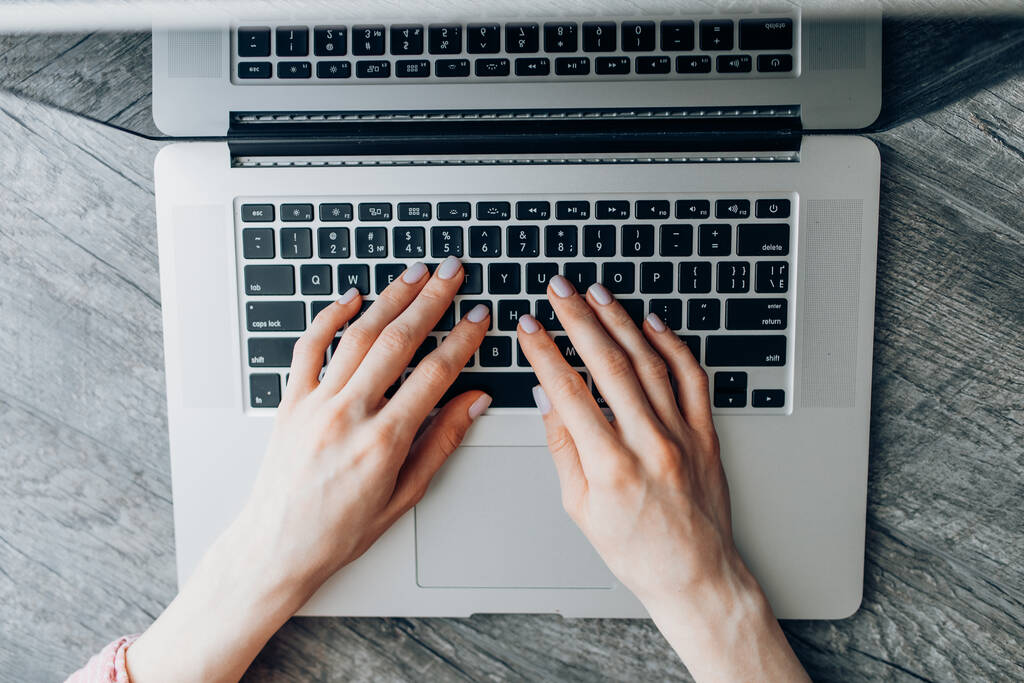 Közelkép egy üzletasszony kezéről, amint laptopot használ és gépel egy asztali számítógépen. - Fotó, kép