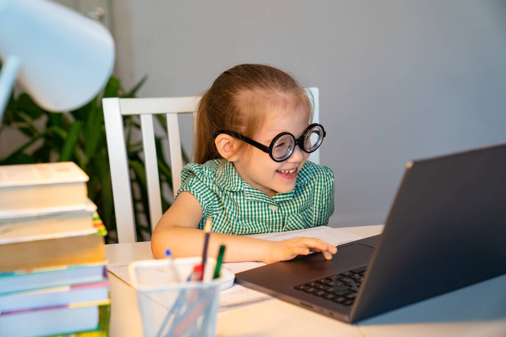 divertida niña en gafas grandes aprendizaje en el ordenador portátil
. - Foto, Imagen