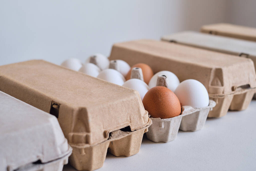 Cardboard boxes with chicken eggs. Boxes with uncooked eggs in table. Natural organic farm product. Preparing for Easter holiday. Fresh food delivery, carton package. Raw ingredient for cooking eat - Photo, Image