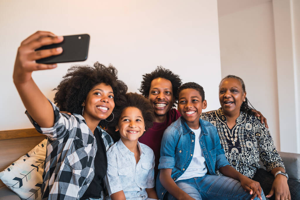 Porträt einer afrikanisch-amerikanischen Mehrgenerationenfamilie, die zu Hause ein Selfie mit dem Handy macht. Familien- und Lifestylekonzept. - Foto, Bild