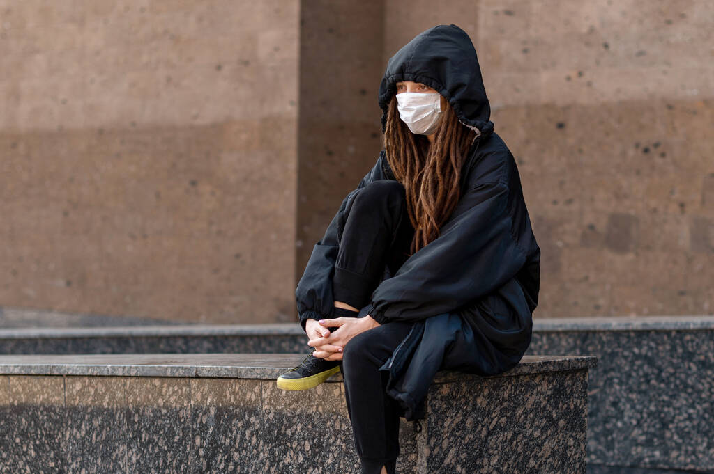 Korkmuş kız kapüşonlu ve tıbbi bir maske takıyordu. Salgın koronavirüs. bulaşıcı hastalıkların önlenmesi, hijyen ürünleri - Fotoğraf, Görsel