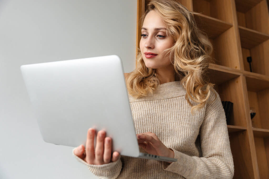 Picture of a pretty young woman indoors at home using laptop computer. - Photo, Image