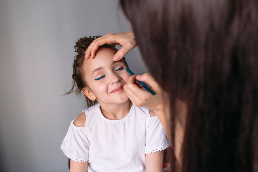 mladá matka dělá make-up pro svou dceru, ráno, světlo z okna, veselá dcera hodně mluví - Fotografie, Obrázek