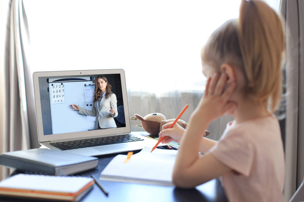 Дистанційне навчання. Весела маленька дівчинка використовує ноутбук комп'ютер, який навчається через онлайн систему електронного навчання
 - Фото, зображення