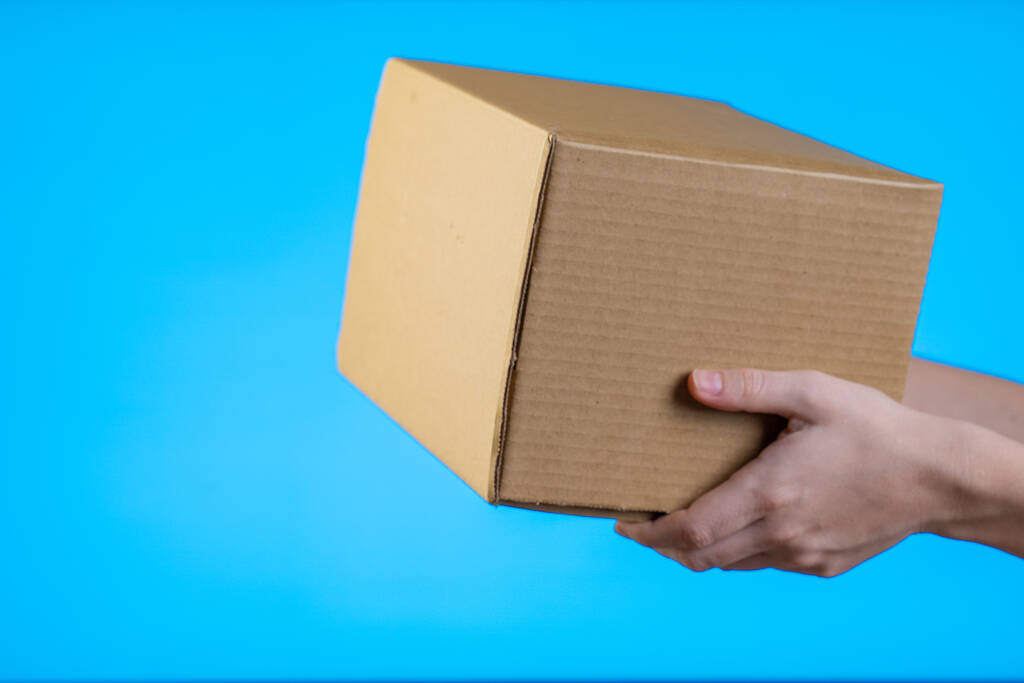 Shop assistant gives the parcel, isolated, blue background - Photo, Image