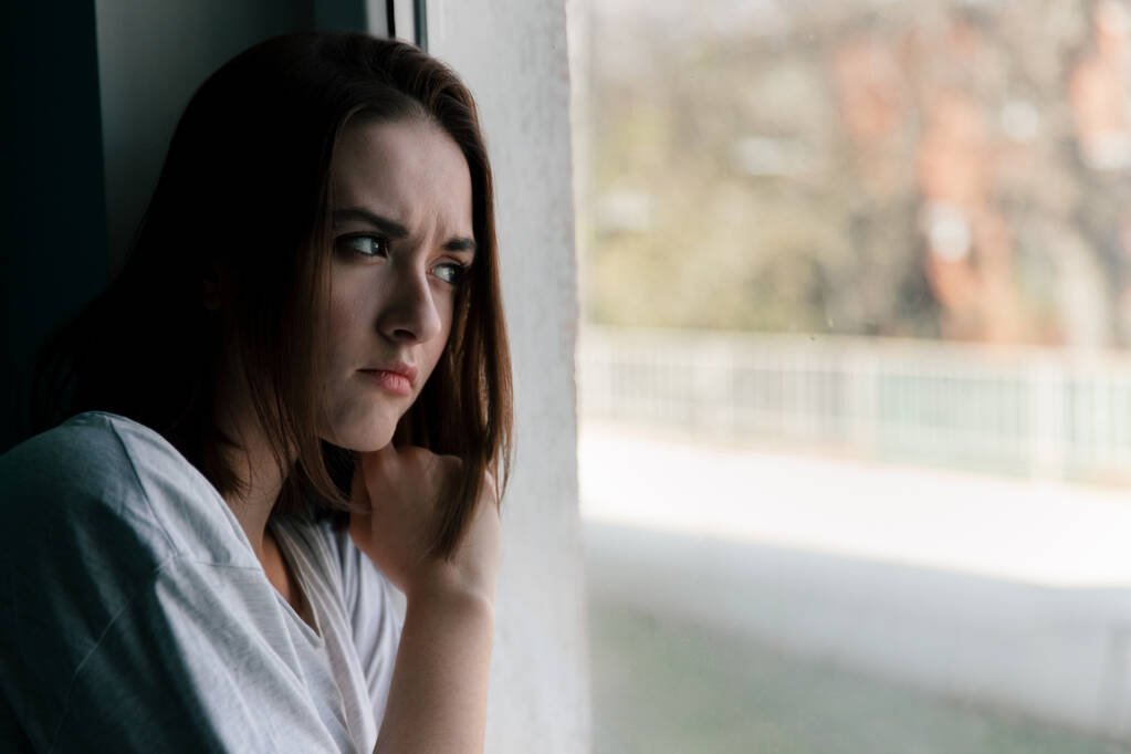 Девушка грустит в доме у окна в самоизоляции
 - Фото, изображение