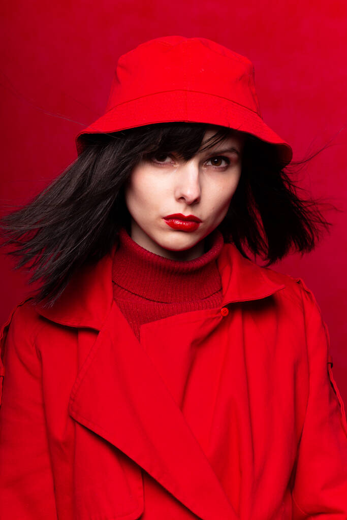 meisje in rode kleren, rode achtergrond, rode lippen, de wind in haar haar - Foto, afbeelding
