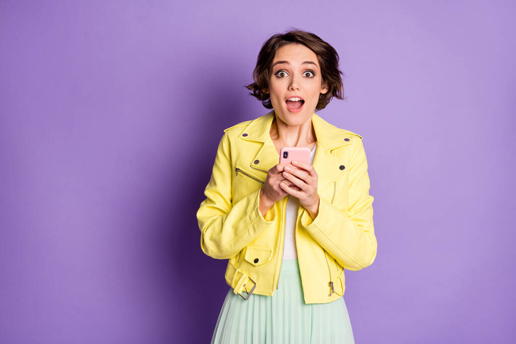 Portrait of funky positive astonished girl use smartphone get many instagram followers impressed scream wear yellow clothes isolated over violet color background - Photo, Image