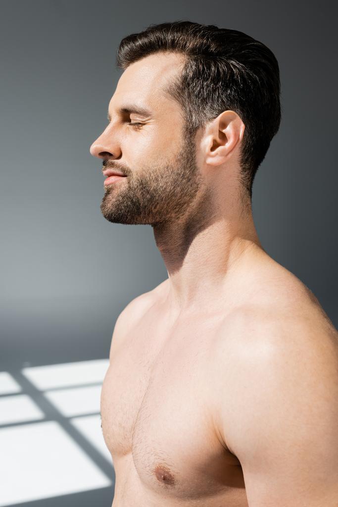 vue latérale d'un homme beau et torse nu avec les yeux fermés sur le gris
  - Photo, image