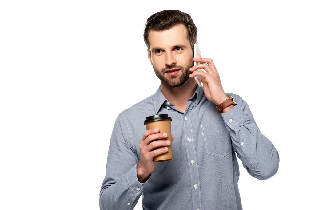 όμορφος άντρας που κρατάει χάρτινο κύπελλο και μιλάει σε smartphone απομονωμένο σε λευκό  - Φωτογραφία, εικόνα