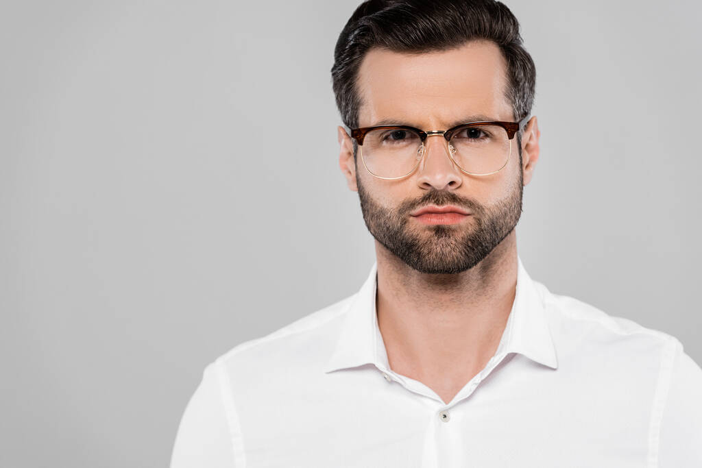 hombre de negocios barbudo y guapo en gafas mirando cámara aislada en gris
  - Foto, imagen