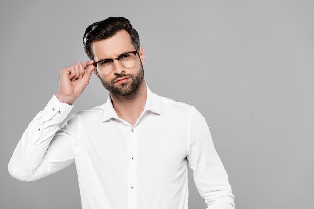 pohledný podnikatel dotýkání brýle izolované na šedé  - Fotografie, Obrázek