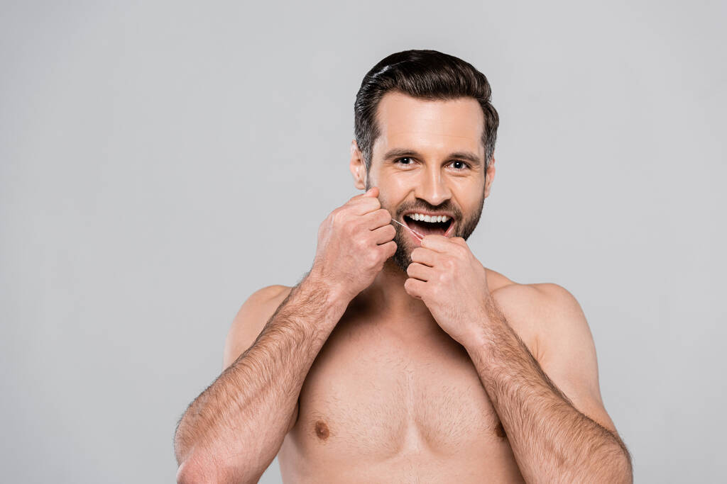 homem feliz e muscular segurando fio dental isolado em cinza
  - Foto, Imagem