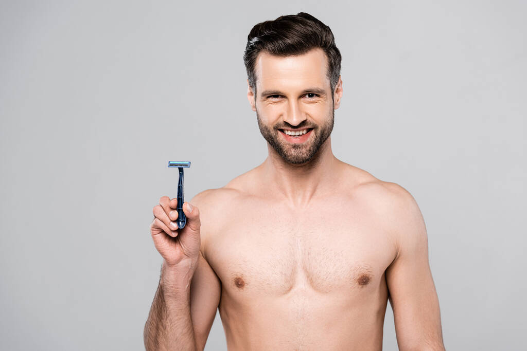 handsome man holding razor while smiling isolated on grey  - Photo, Image