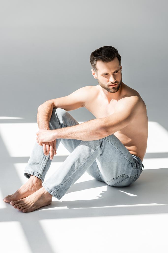 soleil sur homme torse nu en jeans bleu assis sur gris
  - Photo, image