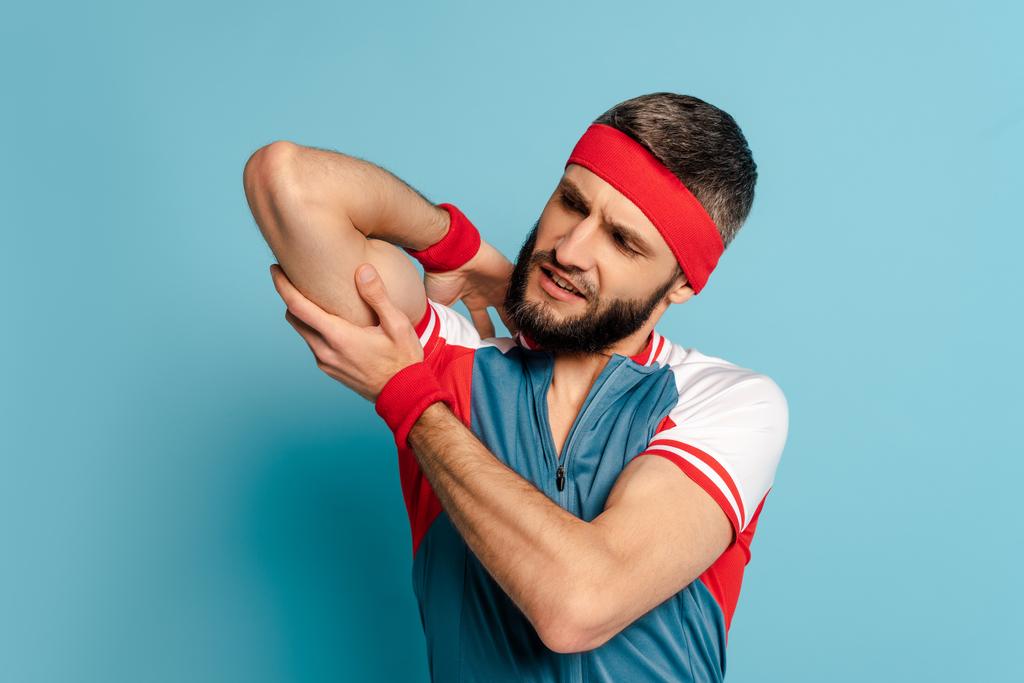 deportista con estilo mirando bíceps sobre fondo azul
 - Foto, imagen