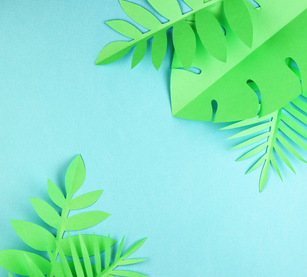 verschillende tropische bladeren op een blauwe achtergrond, bovenaanzicht. exotische achtergrond met papier groene bladeren - Foto, afbeelding