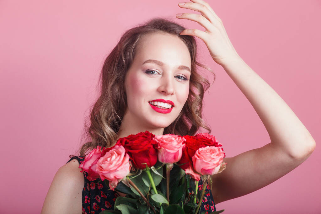 Happy laughing romantic woman holding flowers on pink background. Beauty woman with roses - Photo, Image
