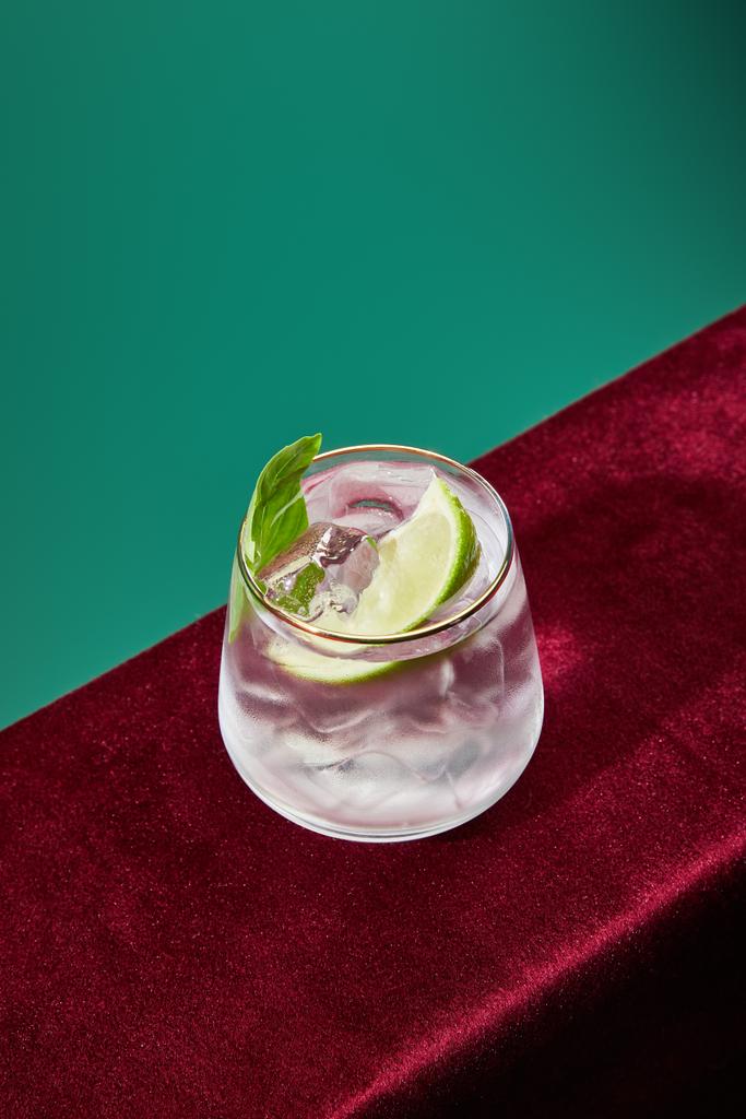 High angle view of glass with fresh mojito, mint and lime slice on green and black background - Photo, Image