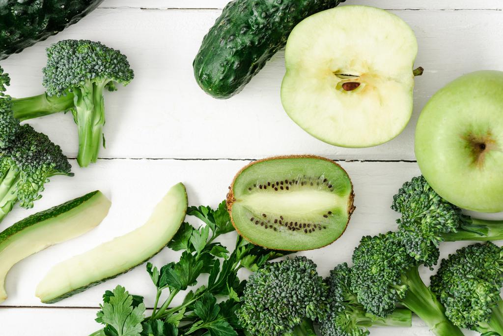 bovenaanzicht van verse groene groenten en fruit op witte houten ondergrond - Foto, afbeelding