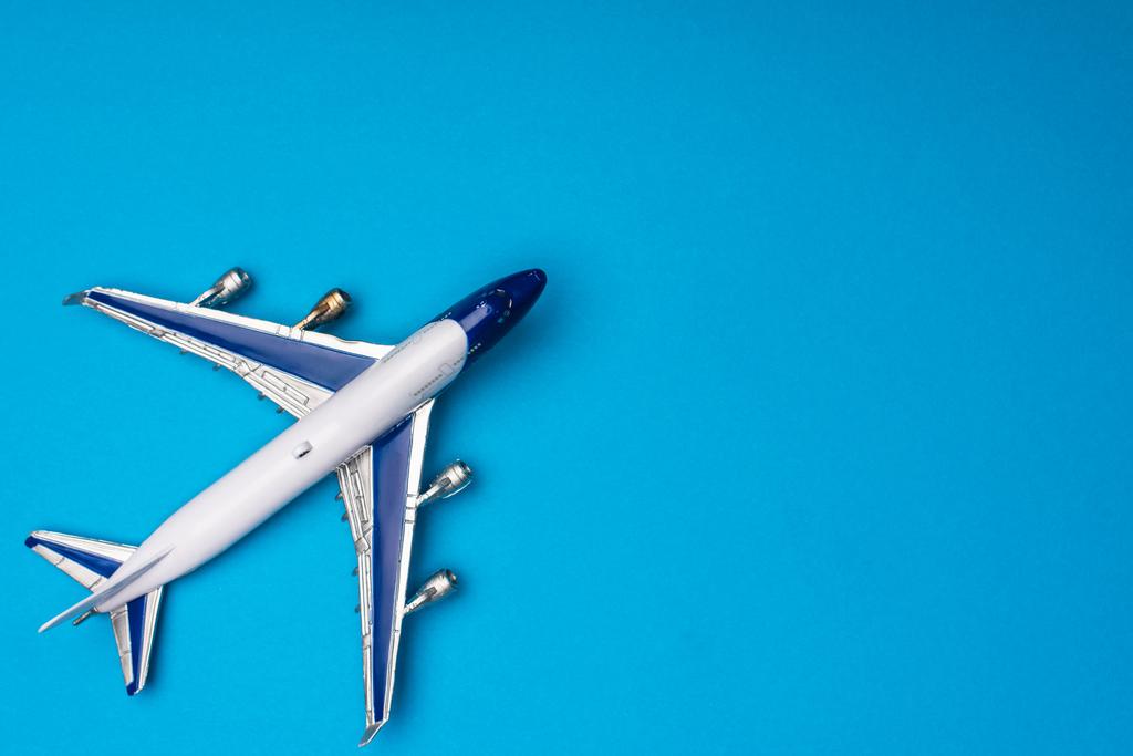 Bovenaanzicht van speelgoedvliegtuig op blauwe achtergrond met kopieerruimte - Foto, afbeelding
