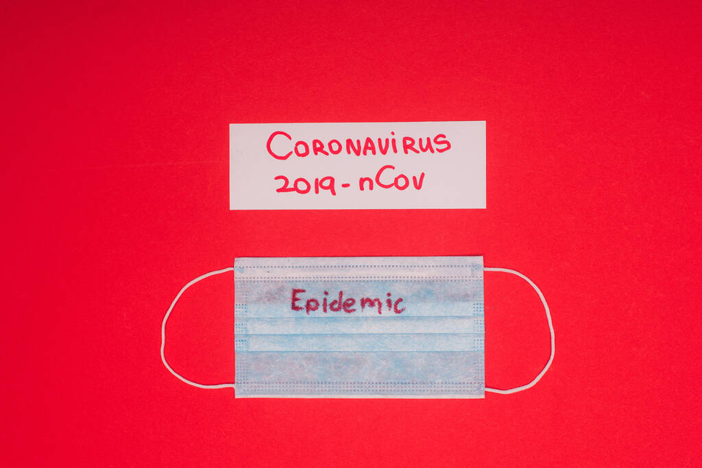 Vista superior de la máscara médica con epidemia y tarjeta con coronavirus 2019-nCov letras aisladas en rojo
  - Foto, Imagen