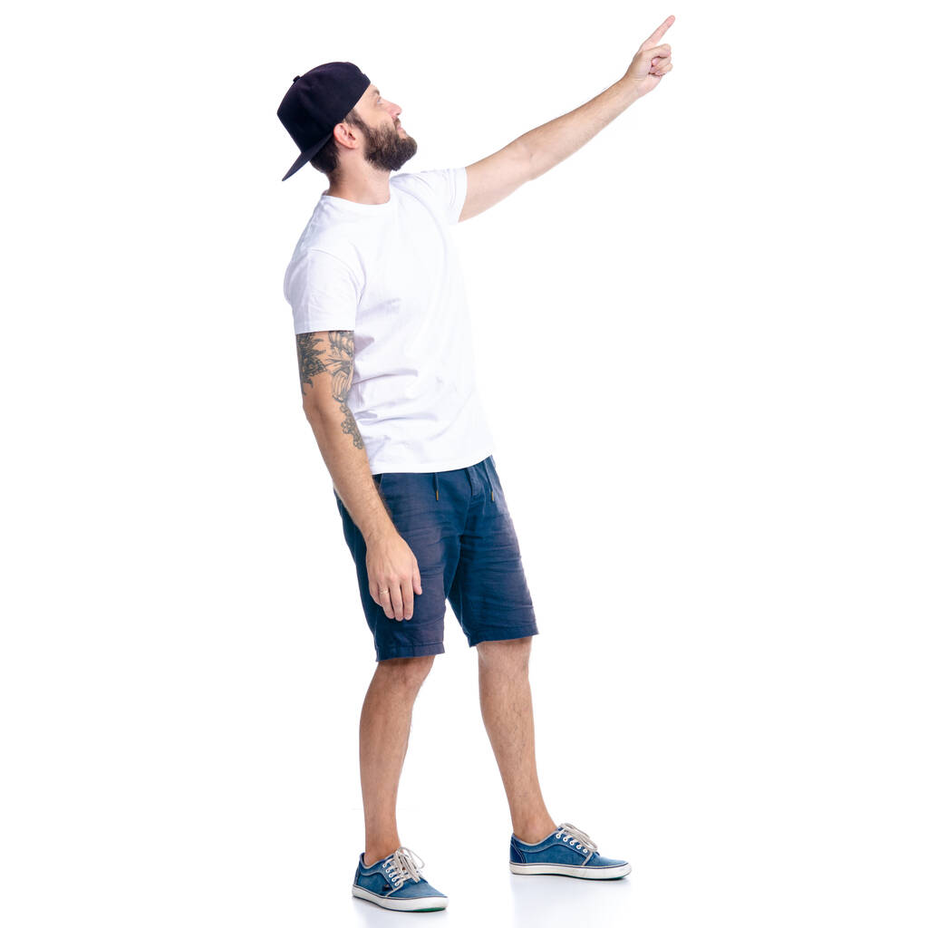 Hombre en pantalones cortos y gorra de pie mostrando señalando
 - Foto, imagen