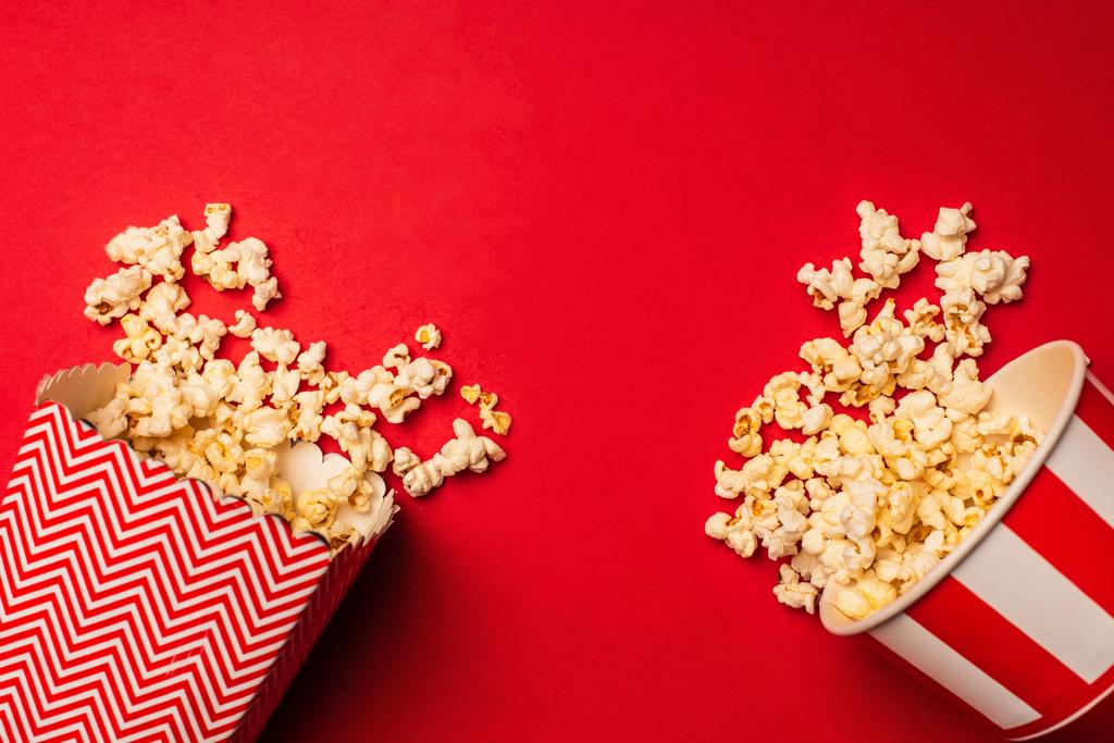 Draufsicht auf Eimer mit leckerem Popcorn auf rotem Hintergrund - Foto, Bild