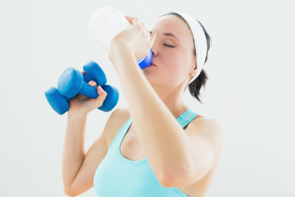 Toned woman with dumbbells drinking water - Photo, Image