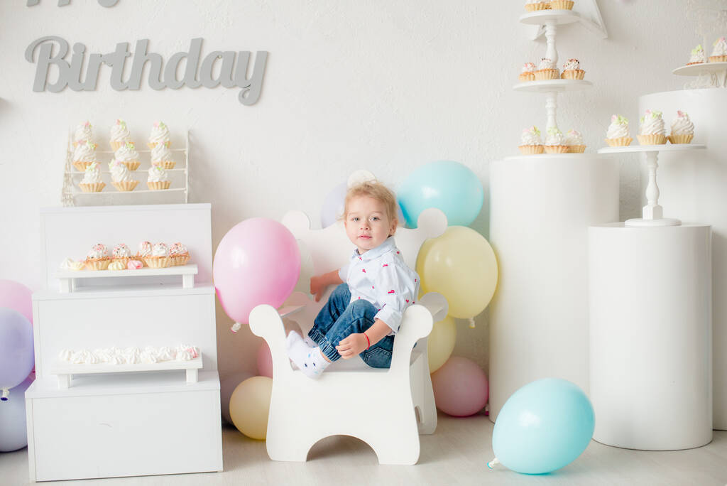 Roztomilý chlapeček s blond vlasy na jeho narozeniny na dětské párty s balónky a koláčky. Dětská párty. Balónky - Fotografie, Obrázek