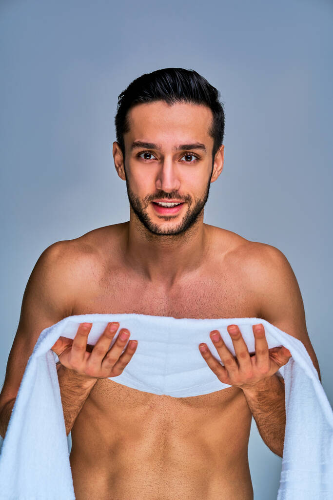 Gros plan heureux bronzé homme nu avec une serviette de bain blanche dans les mains
 - Photo, image