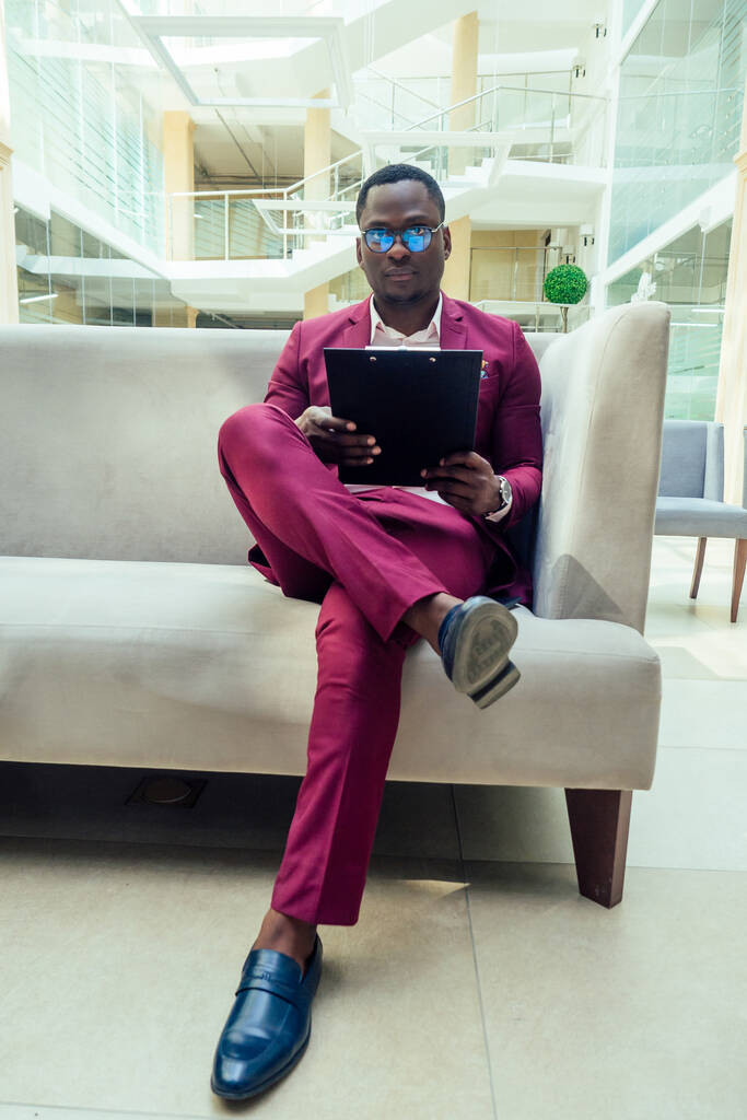 Afryki amerykański stylowy mężczyzna w Marsala kurtka działa w nowoczesny Duży biuro - Zdjęcie, obraz
