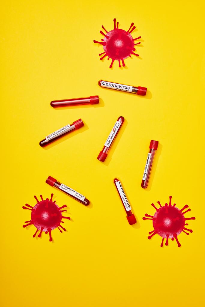 horní pohled na zkumavky s nápisem koronavirového testu a nakresleným virem na žluté - Fotografie, Obrázek