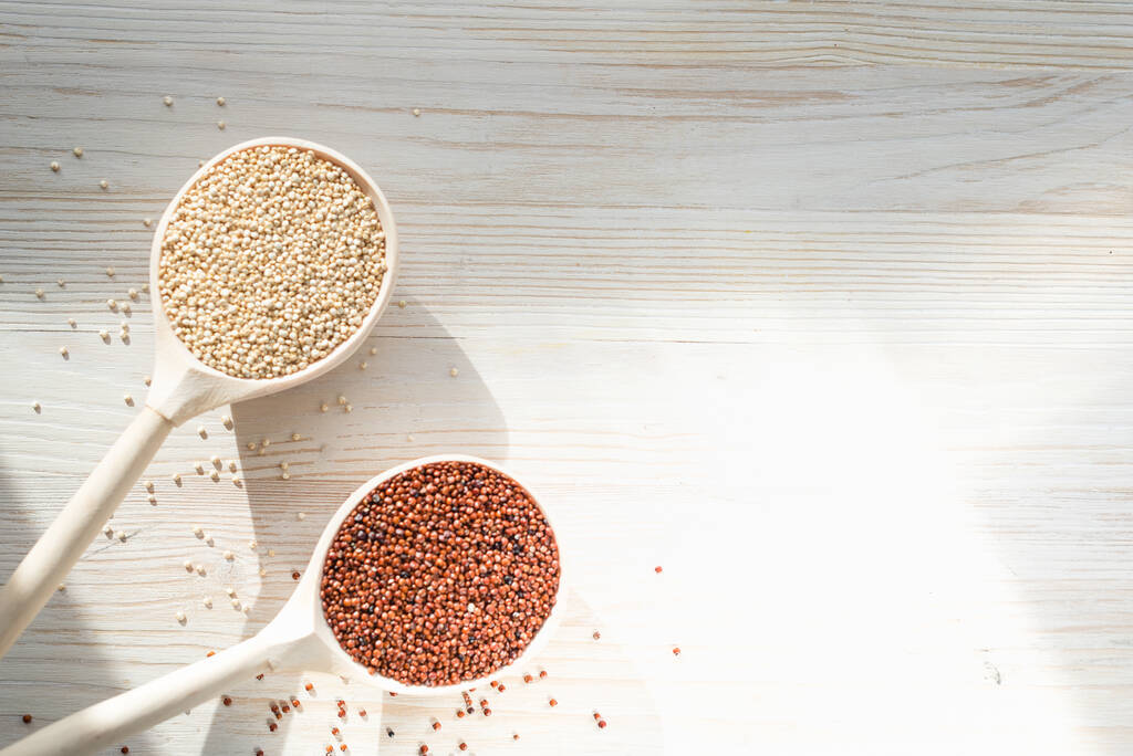 quinoa blanc et rouge dans des cuillères en bois sur un fond en bois
 - Photo, image