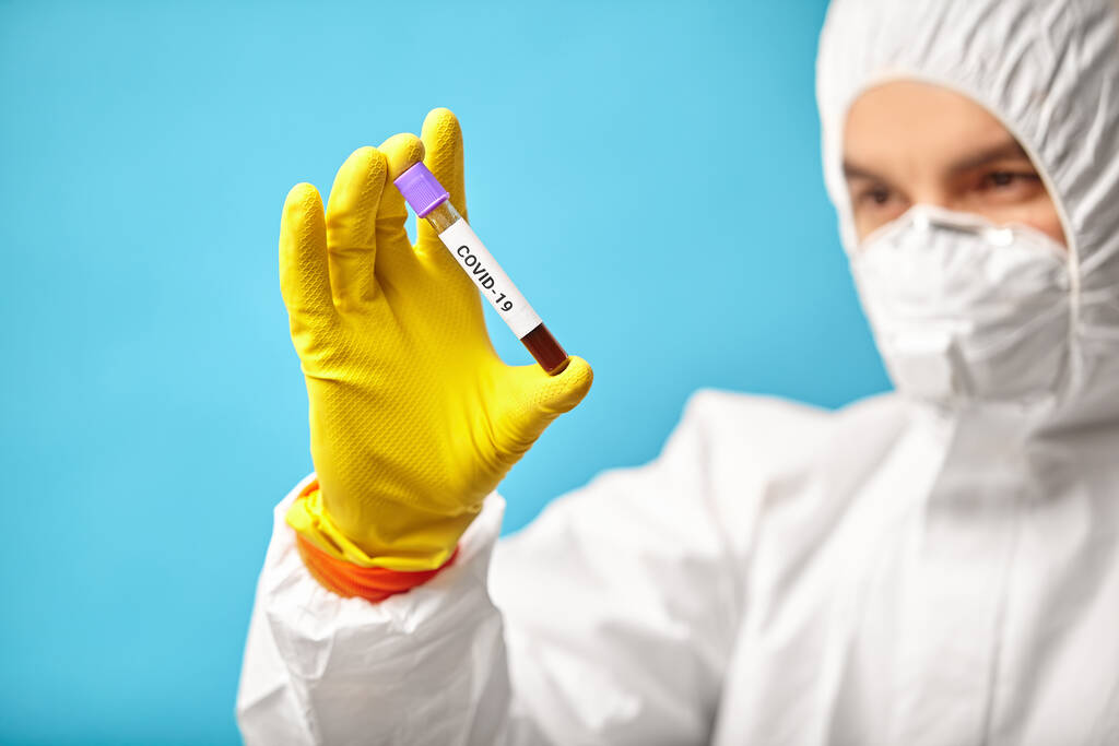 Technicien de laboratoire portant masque respirateur et combinaison de protection tenir tube médical pour test express sur coronavirus
. - Photo, image