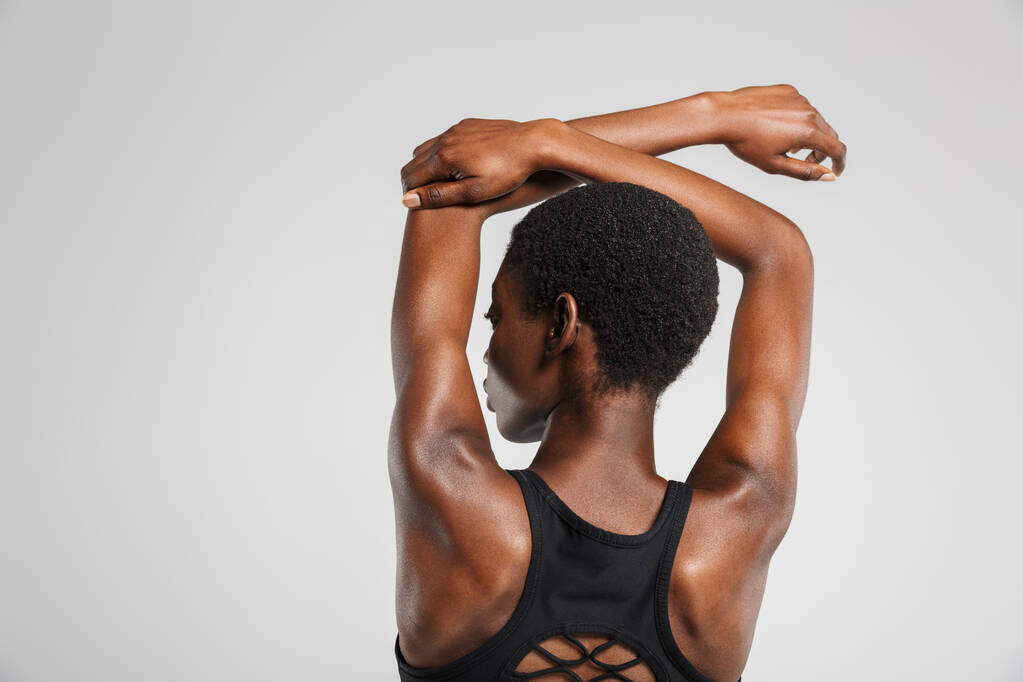 Image from back african american woman stretching her arms while working out isolated over white background - Photo, Image