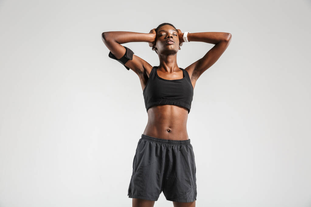 Bild einer afrikanisch-amerikanischen Sportlerin, die ihren Kopf fasst, während sie isoliert auf weißem Hintergrund trainiert - Foto, Bild