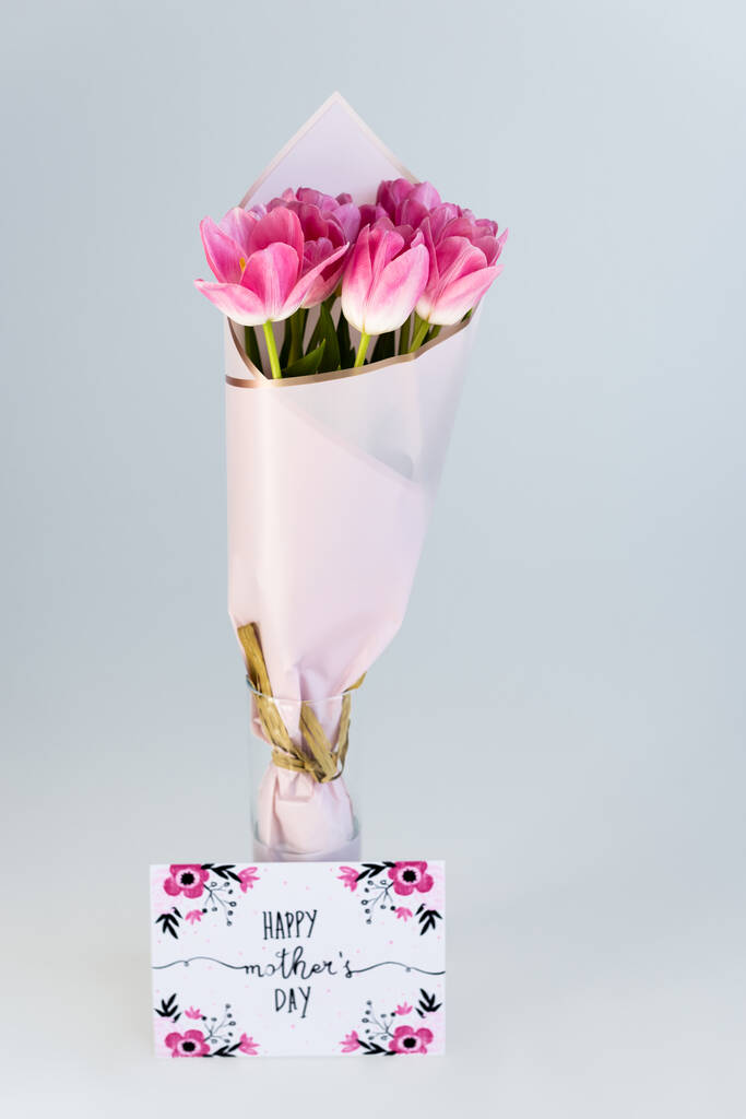 tulipes roses dans un vase près de la carte de vœux avec joyeux lettrage de la fête des mères isolé sur gris
 - Photo, image