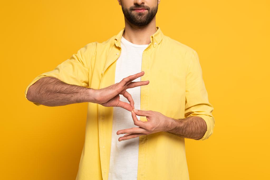 Cropped view of man showing interpretation sign in deaf and dumb language on yellow background - Zdjęcie, obraz
