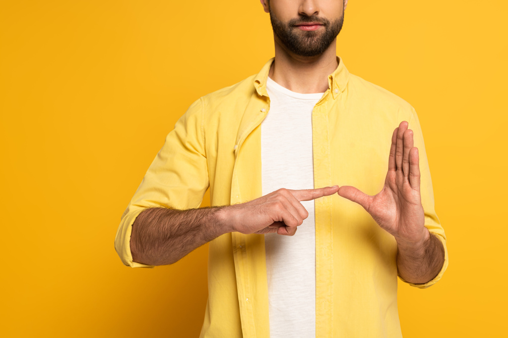 Καλλιεργημένη άποψη του ανθρώπου που δείχνει χειρονομία από τη νοηματική γλώσσα σε κίτρινο φόντο - Φωτογραφία, εικόνα