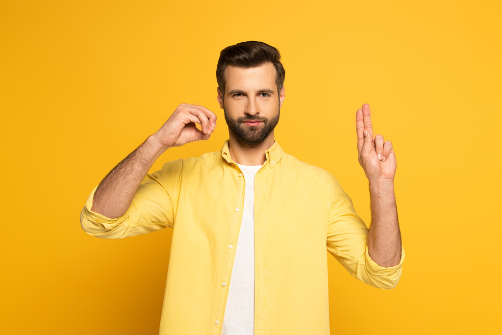 Handsome man showing letters in deaf and dumb language on yellow background - Φωτογραφία, εικόνα