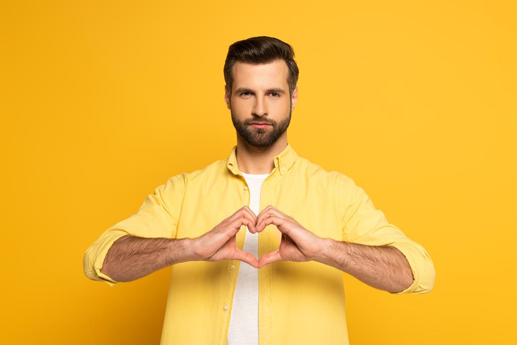 Красивий чоловік показує знак кохання на жовтому тлі
 - Фото, зображення