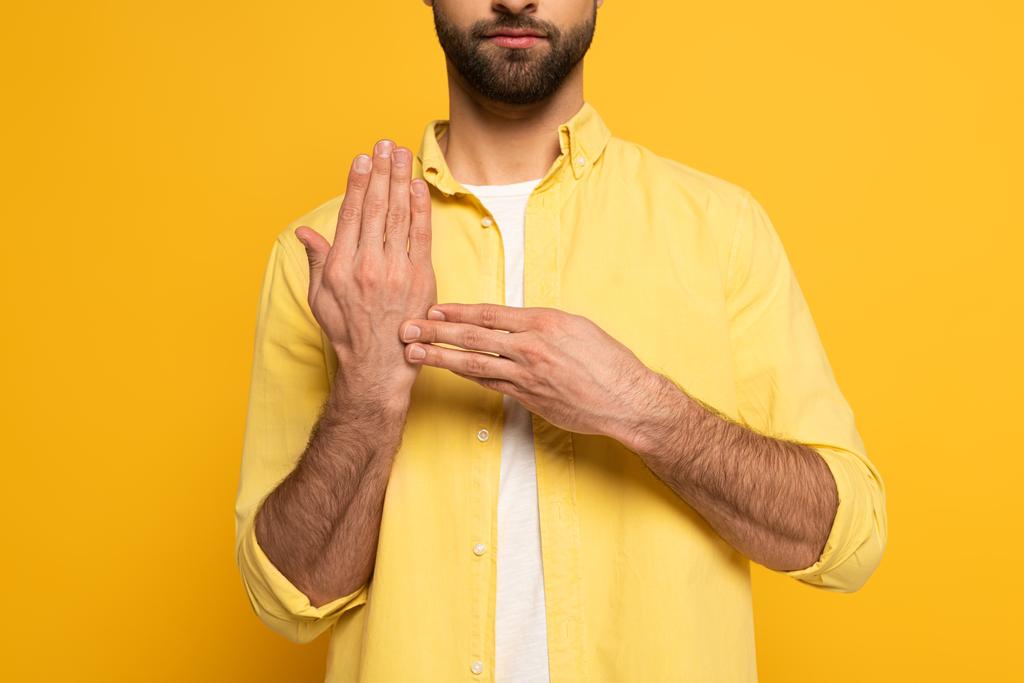 黄色の背景に手話からジェスチャーを示す男の作物ビュー - 写真・画像