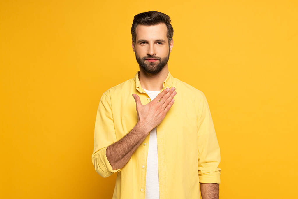 Handsome man showing gesture from sign language on yellow background - Photo, Image