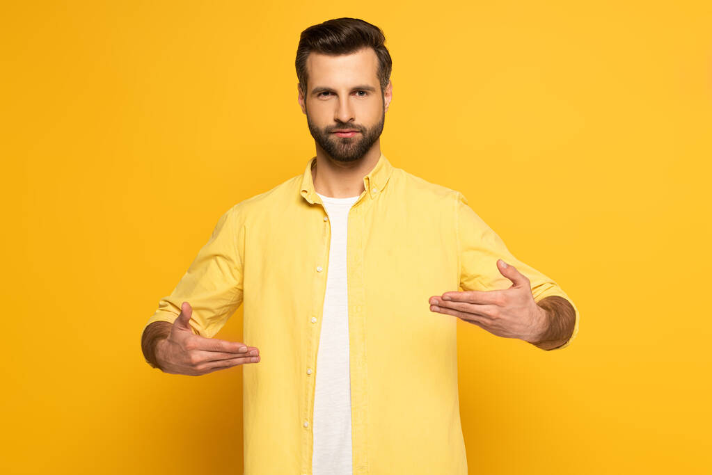 Hombre mirando a la cámara mientras usa lenguaje sordo y mudo sobre fondo amarillo
 - Foto, Imagen